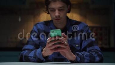 20多岁的年轻人手里拿着手机坐在黑暗中。 男人`手拿着手机。